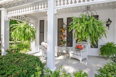 The covered front porch has views of the grounds and trees and manicured landscape