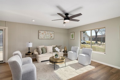 Living room with new floors and ceiling fan and a large window over looking the front of the home.