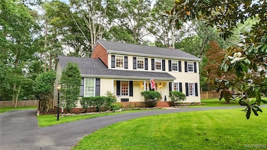 Colonial home featuring asphalt driveway, covered