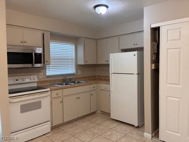 Kitchen featuring white appliances, light countertops, light tile patterned flooring, and white cabinetry