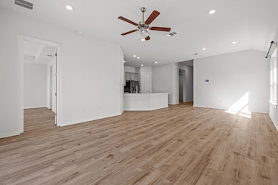 Unfurnished living room featuring light wood finished floors, a ceiling fan, recessed lighting, and vaulted ceiling