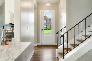 Foyer entrance featuring dark wood finished floors, plenty of natural light, baseboards, and stairs