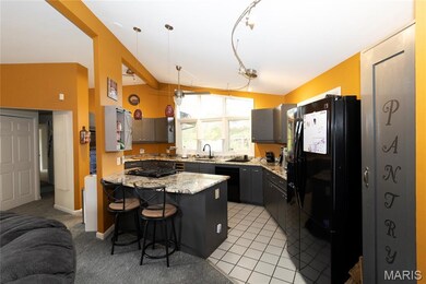 Kitchen featuring black appliances, a kitchen bar, a peninsula, pendant lighting, and light tile patterned floors