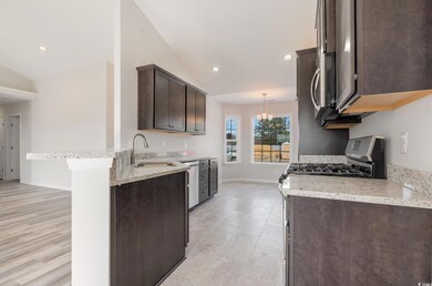Kitchen with dark brown cabinetry, vaulted ceiling, a peninsula, a chandelier, and light stone counters