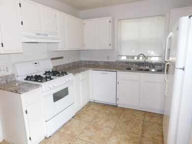 Kitchen featuring light stone counters, a sink, w