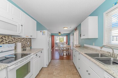 Kitchen featuring white cabinetry, sink, white app