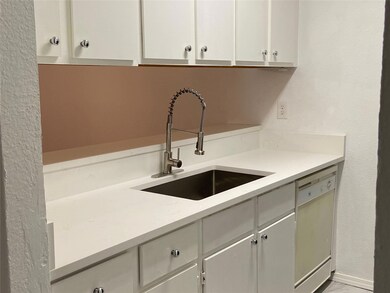 Kitchen featuring dishwasher, white cabinetry, and