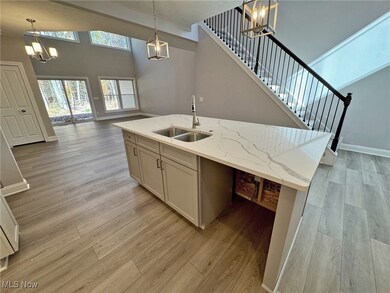 Kitchen featuring a chandelier, quartz countertops, LVP flooring, hanging light fixtures, and a towering ceiling