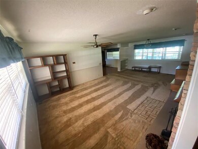 Unfurnished living room featuring a textured ceiling, a ceiling fan, and carpet