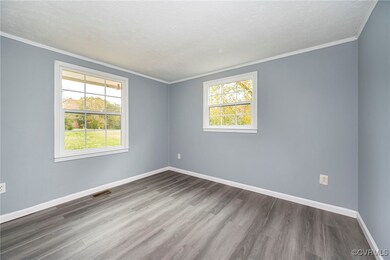 Empty room featuring crown molding, wood-type floo