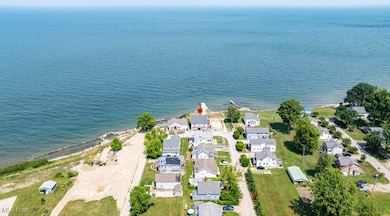 Aerial view of property and surrounding area featuring waterfront with a beach and nearby suburban area