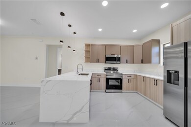 Kitchen featuring a peninsula, light marble finish flooring, stainless steel appliances, light brown cabinetry, and open shelves