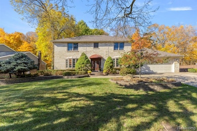 Colonial inspired home featuring a front lawn, brick siding, a garage, and driveway