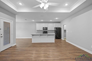 Kitchen featuring white cabinets, dark wood finished floors, black appliances, an island with sink, and recessed lighting