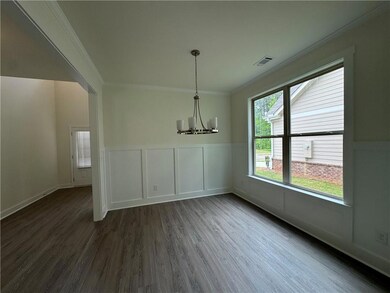 Unfurnished dining area with crown molding, a chandelier, dark wood-style flooring, wainscoting, and a decorative wall