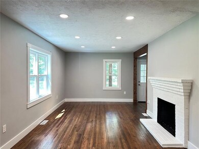 Unfurnished living room with dark wood-type flooring, baseboards, a textured ceiling, recessed lighting, and a fireplace