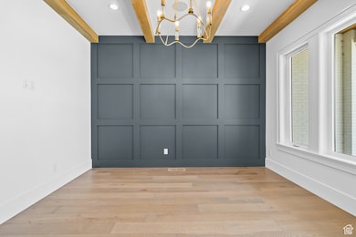 Unfurnished dining area with a decorative wall, a chandelier, plenty of natural light, recessed lighting, and light wood finished floors