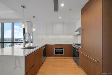 Kitchen featuring modern cabinets, light stone counters, a peninsula, brown cabinets, and recessed lighting