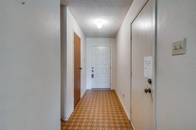Hallway with a textured ceiling and tile patterned flooring