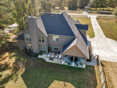 This home features a modern design with a dark roof and light siding. It has a spacious backyard and a cozy covered patio for outdoor relaxation. 