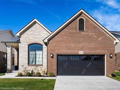 View of front facade with concrete driveway, stone siding, brick siding, a front yard, and a porch