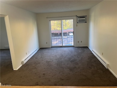 Empty room with a baseboard heating unit, baseboard heating, carpet, and a wall mounted AC