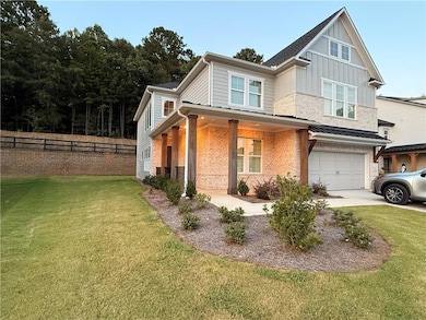 View of front of home with covered porch, an attached garage, brick siding, driveway, and board and batten siding