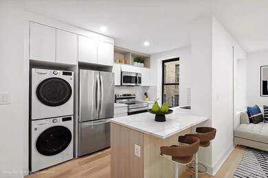 Kitchen featuring stainless steel appliances, light wood-type flooring, a kitchen bar, tasteful backsplash, and white cabinets