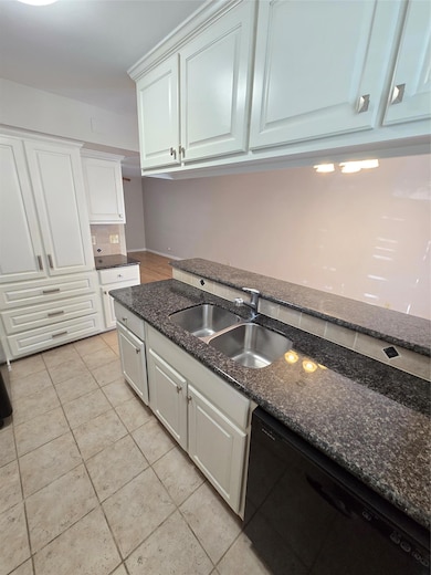 Kitchen with dishwashing machine, dark stone countertops, white cabinetry, and backsplash