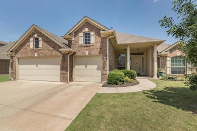 Traditional-style home with brick siding, driveway, a front lawn, an attached garage, and a shingled roof