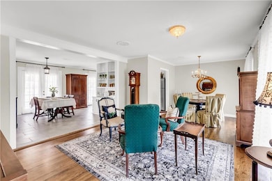 Dining space with wood finished floors, a chandelier, and crown molding