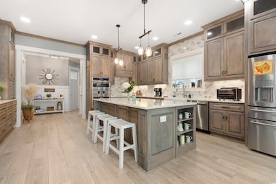Kitchen featuring stainless steel appliances, a sink, light countertops, a kitchen island, and backsplash