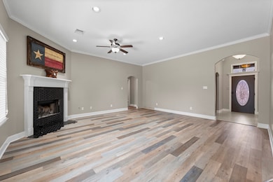 This beautifully designed Family Room blends style and function, featuring wood-look vinyl plank flooring, arched entryways, over-sized baseboards, recessed lighting, crown molding, and rounded drywall corners. A lighted ceiling fan adds both comfort and charm. Conveniently located just off the kitchen, this open-concept space makes it easy to stay connected while entertaining or enjoying everyday moments.