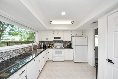 Bright kitchen with white cabinets and appliances,