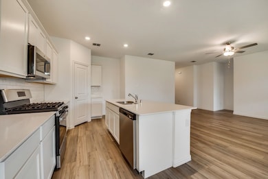 Kitchen with stainless steel appliances, backsplash, light wood-type flooring, recessed lighting, and ceiling fan