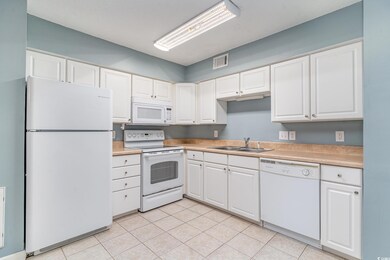Kitchen with white cabinetry, light tile patterned