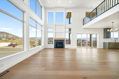 Unfurnished living room with a mountain view, a glass covered fireplace, light wood-style floors, recessed lighting, and a towering ceiling