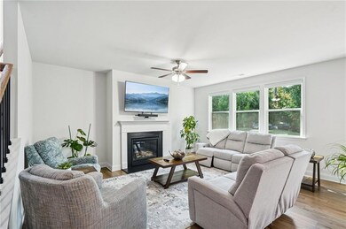 Living room with wood finished floors, a fireplace with flush hearth, and a ceiling fan