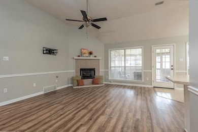 Unfurnished living room featuring wood finished floors, a tile fireplace, ceiling fan, and high vaulted ceiling