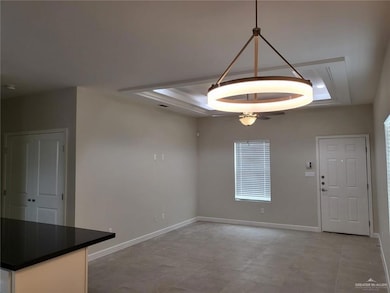Unfurnished dining area featuring a tray ceiling, ceiling fan, and baseboards