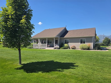 Front of house with covered porch, a yard, and roof with shingles