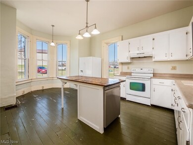 Kitchen featuring white cabinetry, white appliances, pendant lighting, dark hardwood / wood-style flooring, and a kitchen island