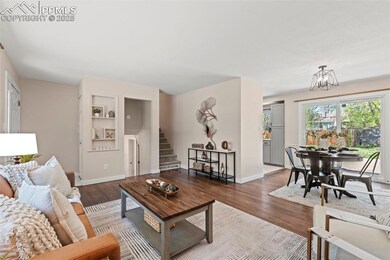 Living room featuring dark wood finished floors, baseboards, stairs, and a chandelier