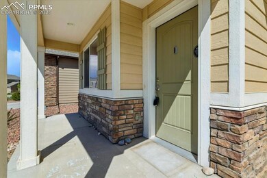 Doorway to property with covered porch, stone siding, and brick siding