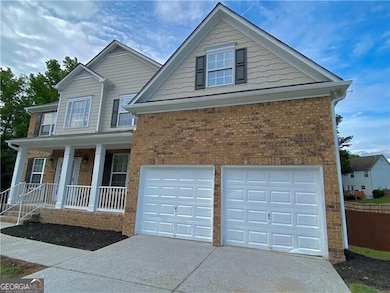 Traditional-style home with an attached garage, brick siding, driveway, and a porch