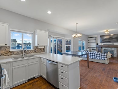 Kitchen featuring white cabinetry, a glass covered fireplace, dark wood-style floors, hanging light fixtures, and recessed lighting