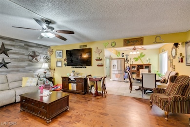 Living room with a ceiling fan, a textured ceiling