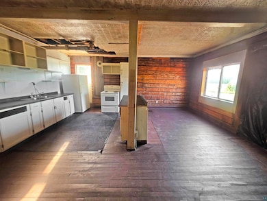 Kitchen with white appliances, dark wood finished floors, dark countertops, and plenty of natural light