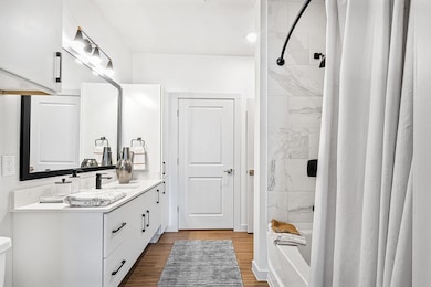 Bathroom with vanity, shower / bath combination with curtain, and dark wood-type flooring
