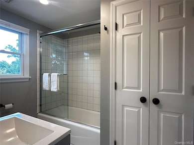 Bathroom featuring bath / shower combo with glass door and vanity, and laundry closet w/ washer/dryer.